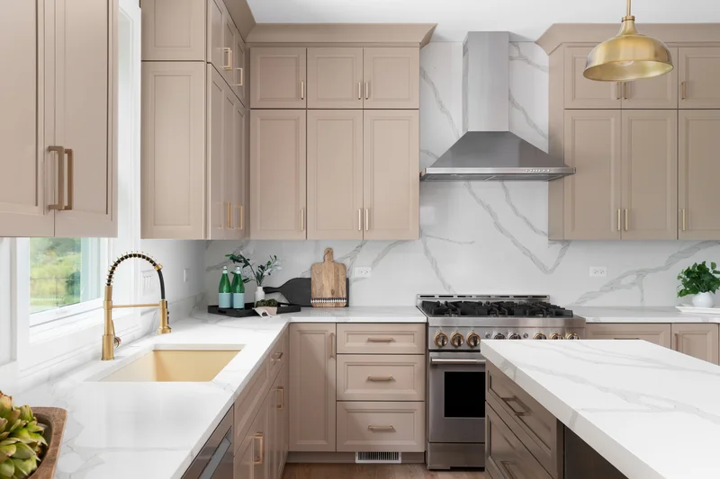 Taupe shaker kitchen cabinets with gold plumbing fixtures and marble backsplash. Taupe shaker kitchen cabinets with gold plumbing fixtures and marble backsplash.