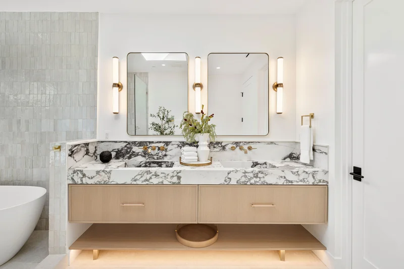 Modern double vanity bathroom remodel with marble countertops and gold fixtures. Modern double vanity bathroom remodel with marble countertops and gold fixtures.